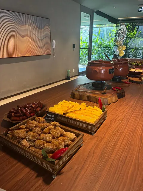 Bandejas de banana à milanesa, laranja fatiada e linguiça, com as panelas de feijoada ao fundo
