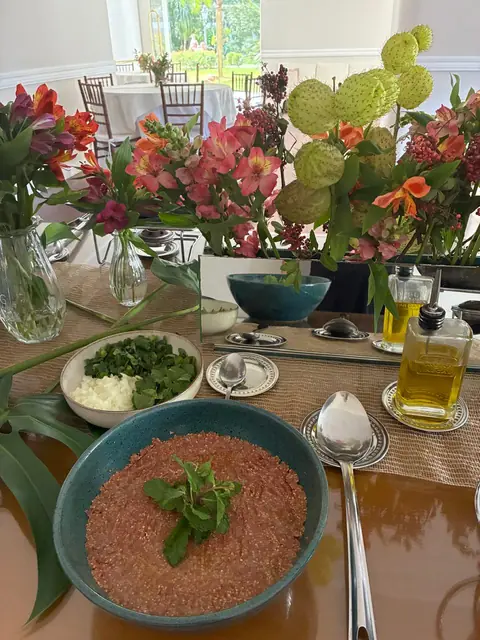 Kibe cru em tigela azul com ramo de hortelã, ao lado de cebola picada, cebolinha e azeite
